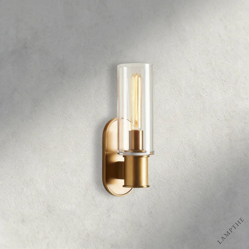 Lampthe Harlin sconce with clear glass shade and brass finish. Modern wall light with arched backplate.
