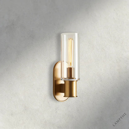 Lampthe Harlin sconce with clear glass shade and brass finish. Modern wall light with arched backplate.