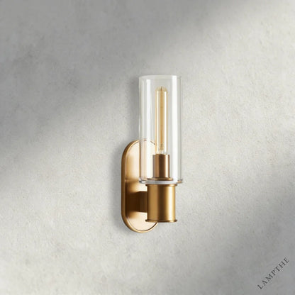 Lampthe Harlin Sconce: brass finish, clear glass cylinder shade, modern wall light with arched backplate.