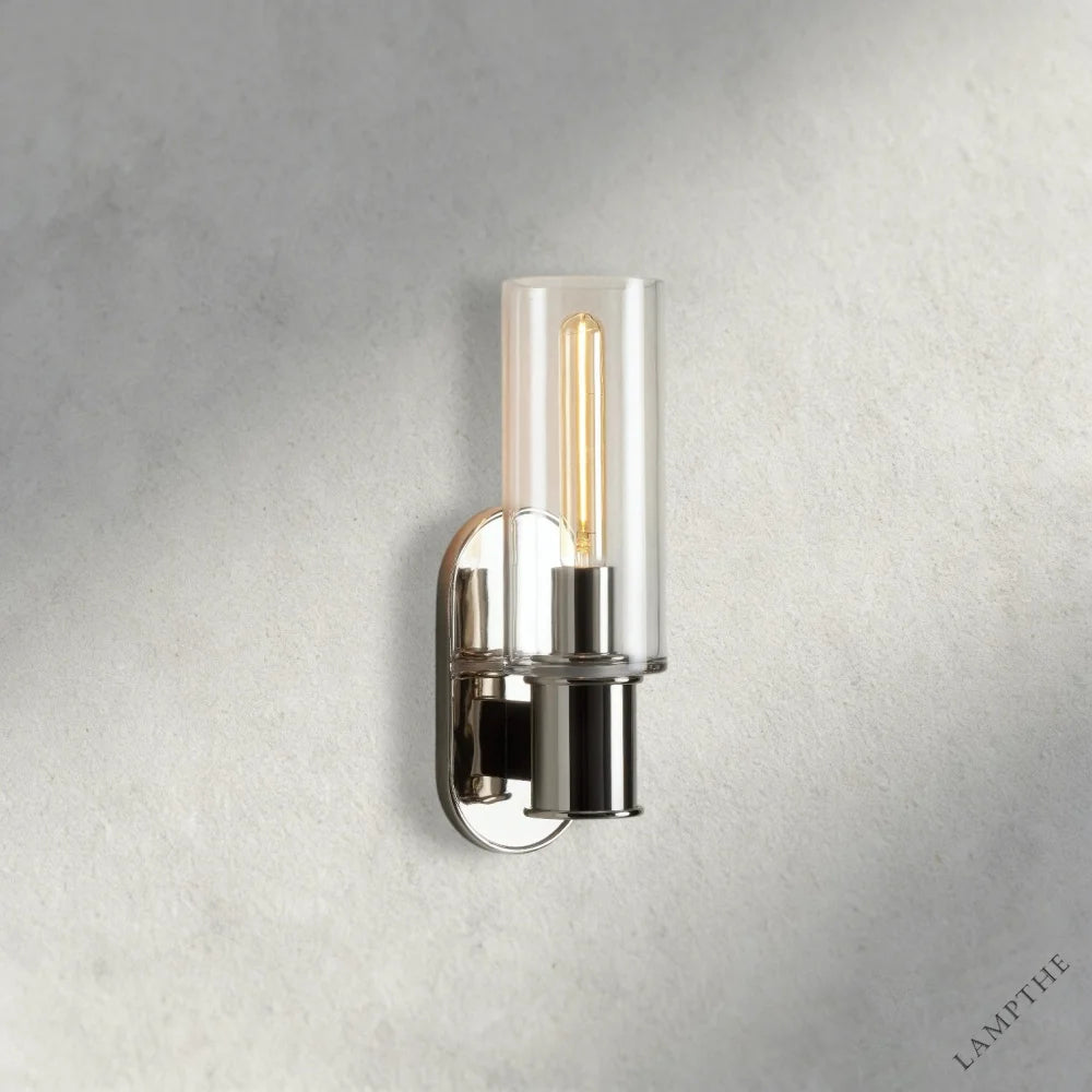 Lampthe Harlin Sconce features a clear glass cylinder shade and a polished nickel finish with an exposed Edison bulb.