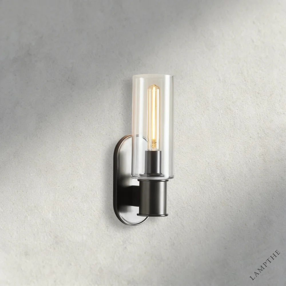 Lampthe Harlin Sconce in clear glass with a dark metal base and exposed Edison bulb, featuring modern sophistication.