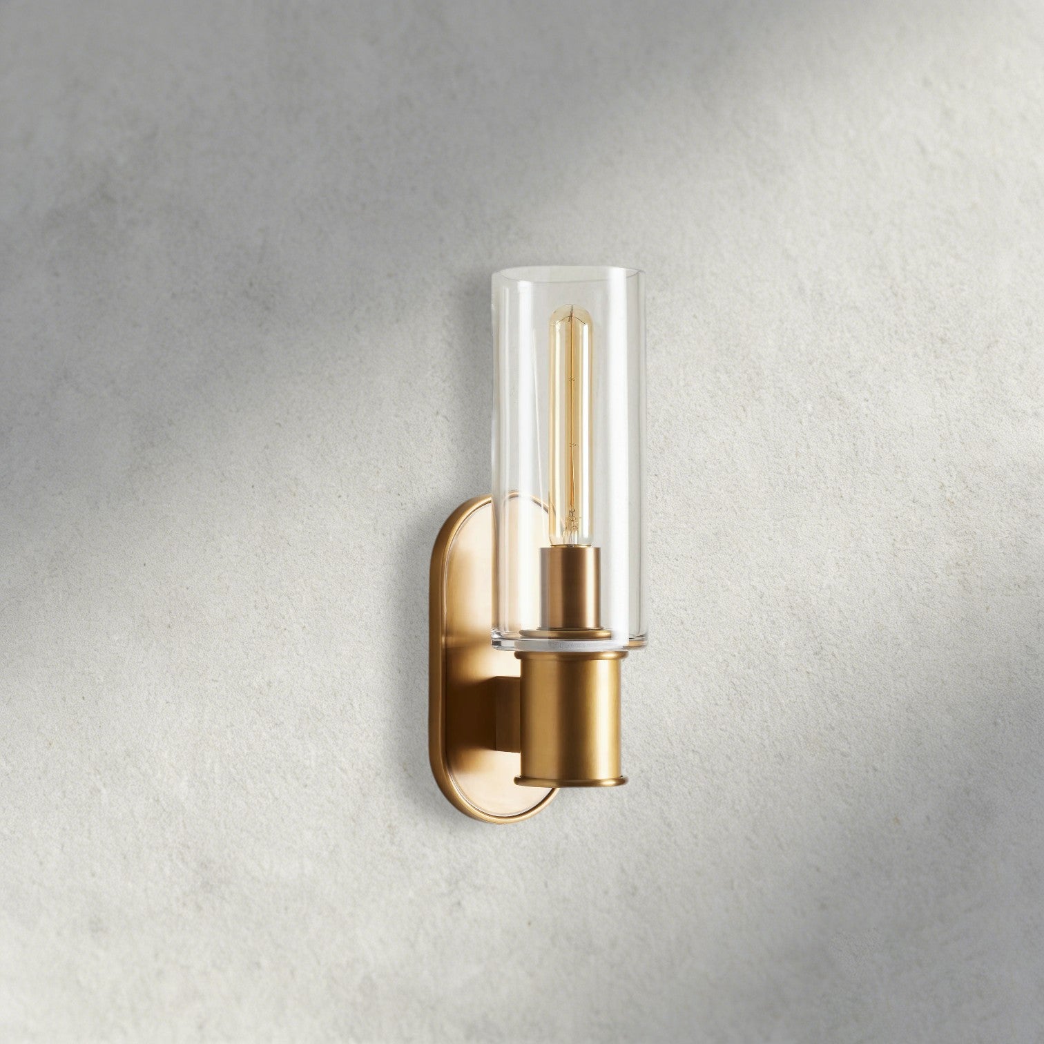 Lampthe Harlin Sconce: brass finish, clear glass cylinder shade, modern wall light with arched backplate.
