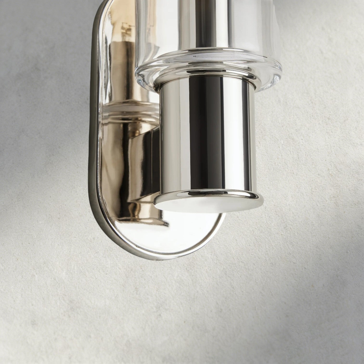 Lampthe Harlin Sconce with clear glass shade and polished nickel finish, featuring a modern oval backplate.