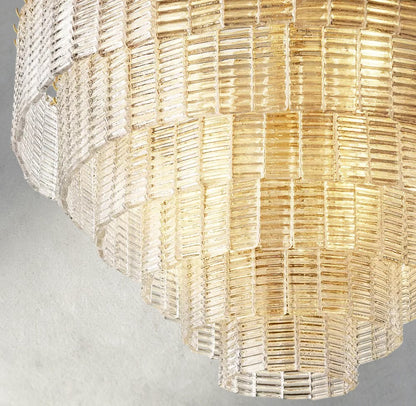 Lampthe Sirene clear glass round chandelier with textured glass cascading in concentric rings, refracting warm light.