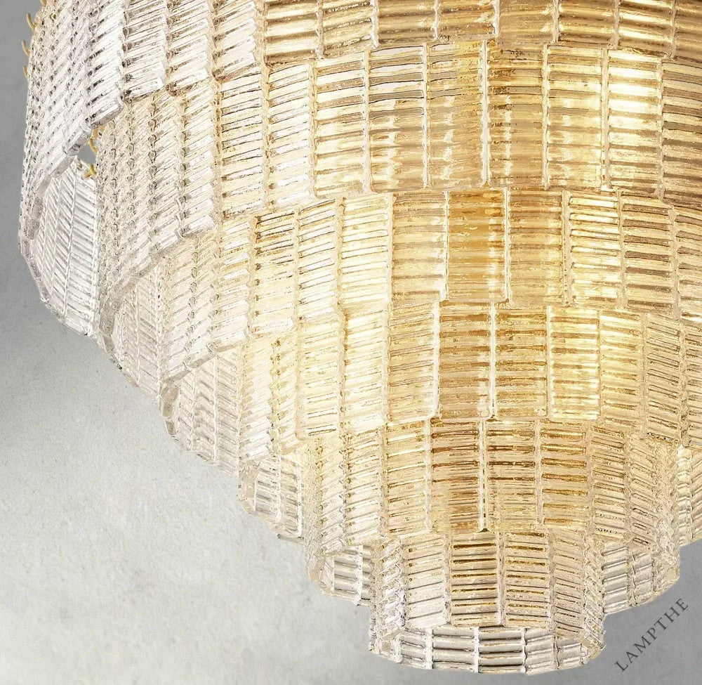 Lampthe Sirene clear glass round chandelier with textured glass cascading in concentric rings, refracting warm light.
